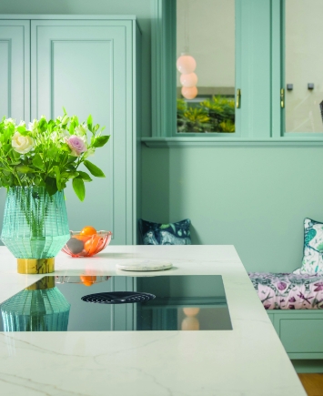 Gold Calacatta worktop with hob cut out beside a built in seating nook in a modern kitchen