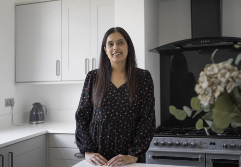Nadiya customer testimonial image in her kitchen with Classic White Quartz worktops visible in the background