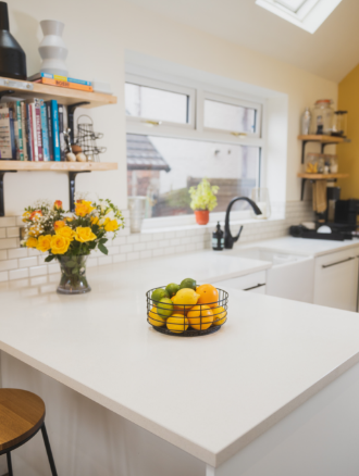 Ice White Quartz island worktop with a fruit bowl on the smooth white surface in a bright kitchen