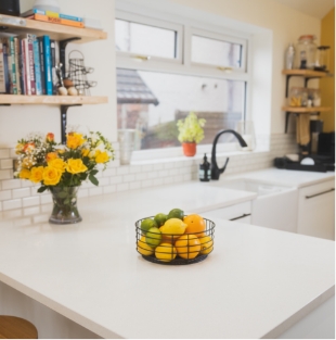 Ice White Quartz island worktop with a fruit bowl on the smooth white surface in a bright kitchen