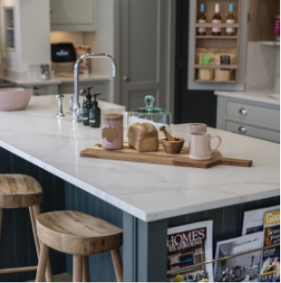 Gold Calacatta kitchen island with warm veining, wooden stools and styled accessories