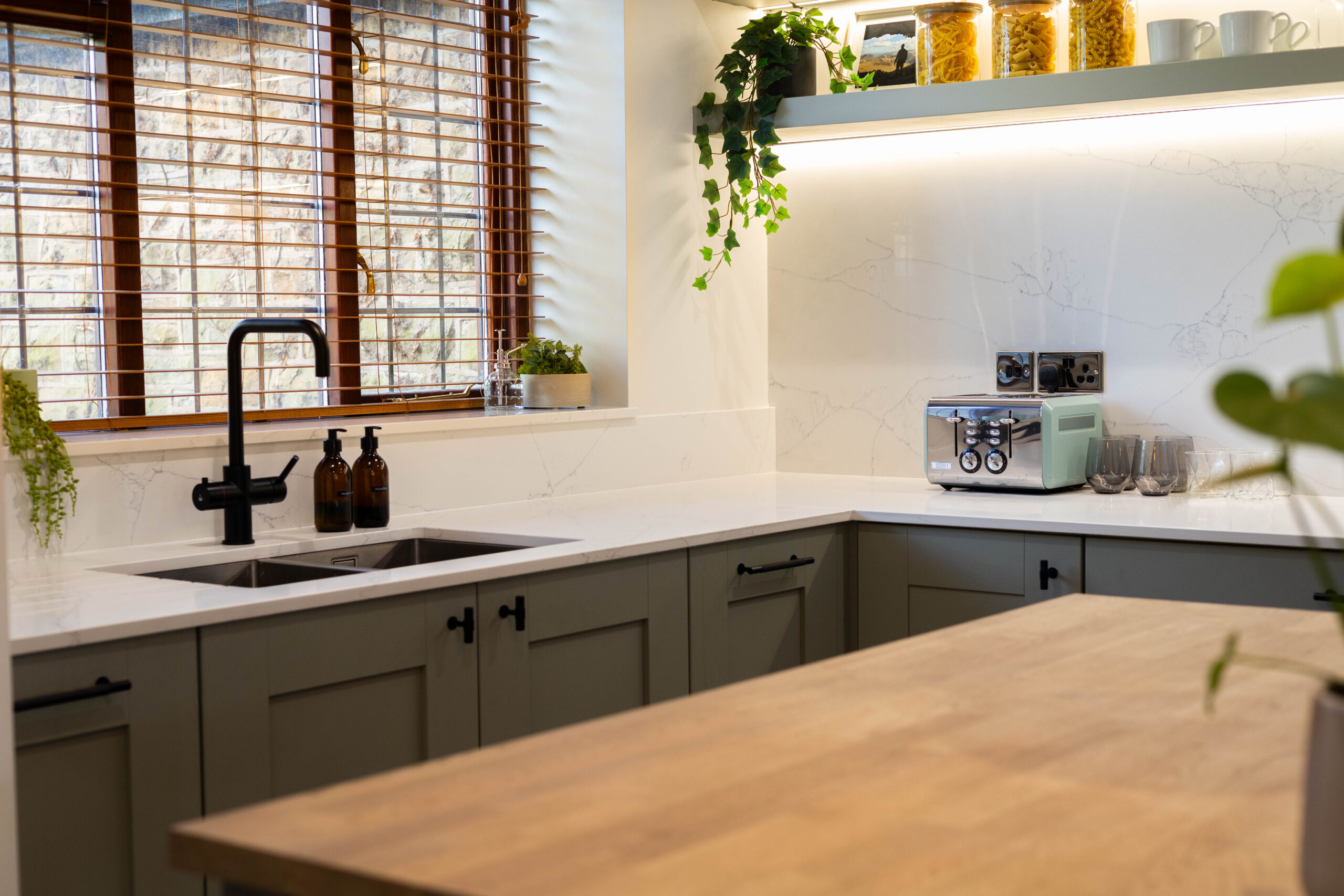 White Macaubus Quartz worktops in a modern kitchen with a sink run and wooden island, showing subtle veining