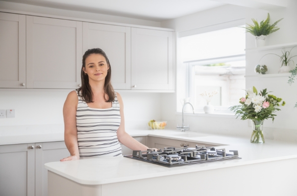 Megan customer testimonial image in her kitchen with Bluetta Carrara Quartz worktops visible around the hob