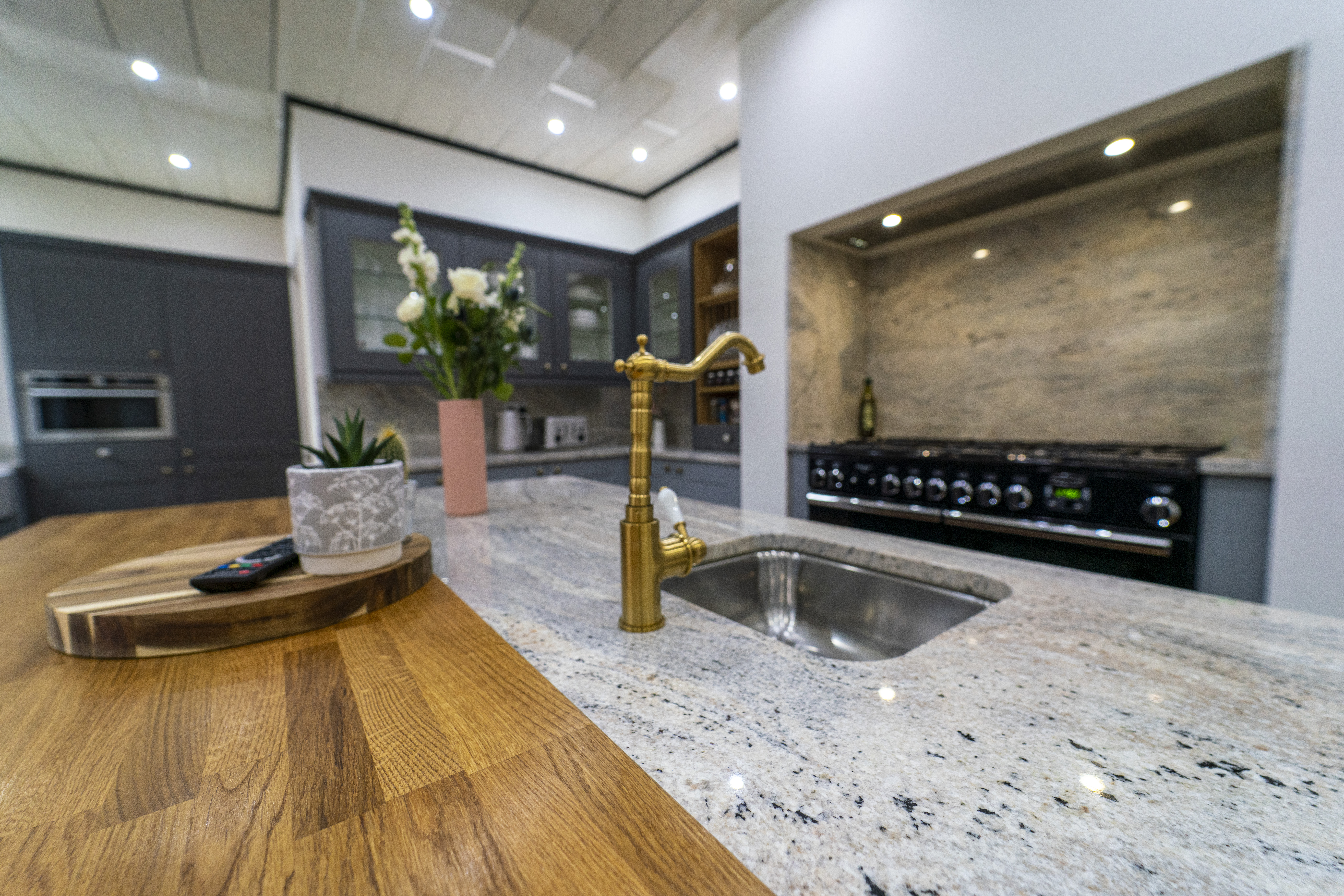 Sink run in a modern kitchen with Ivory Fantasy Granite worktops, brass tap and inset sink, showing the Granite pattern and polished finish.