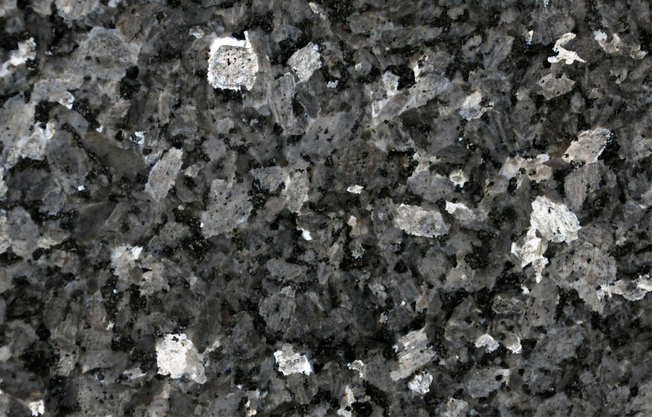 Close up slab photo of Blue Pearl Granite showing a dark base with shimmering blue and silver crystals and natural fleck patterning.