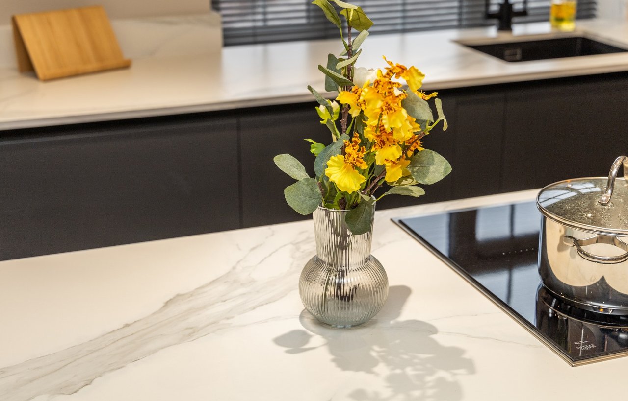 Volakas White Porcelain worktop surface with light grey veining, shown with a vase of flowers on top.