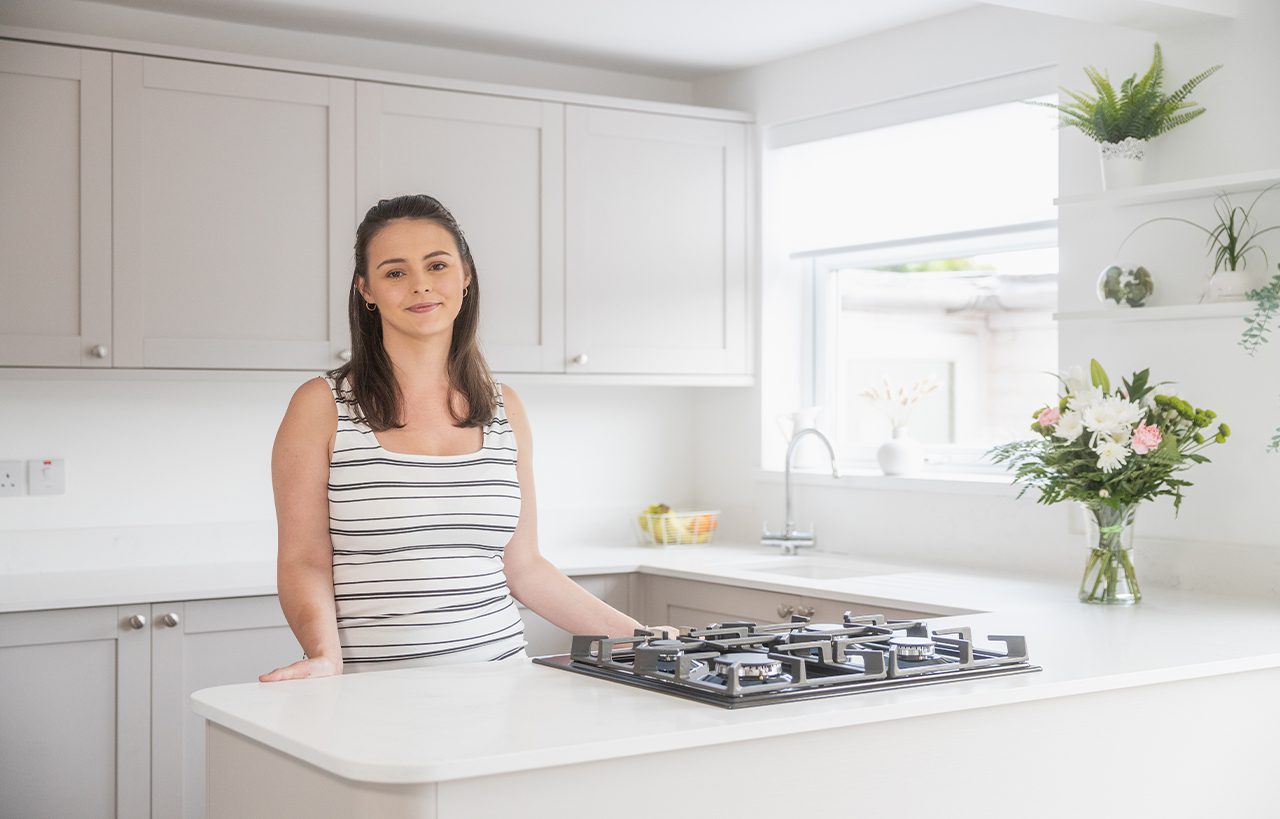 Megan customer testimonial image in her kitchen with Bluetta Carrara Quartz worktops visible around the hob