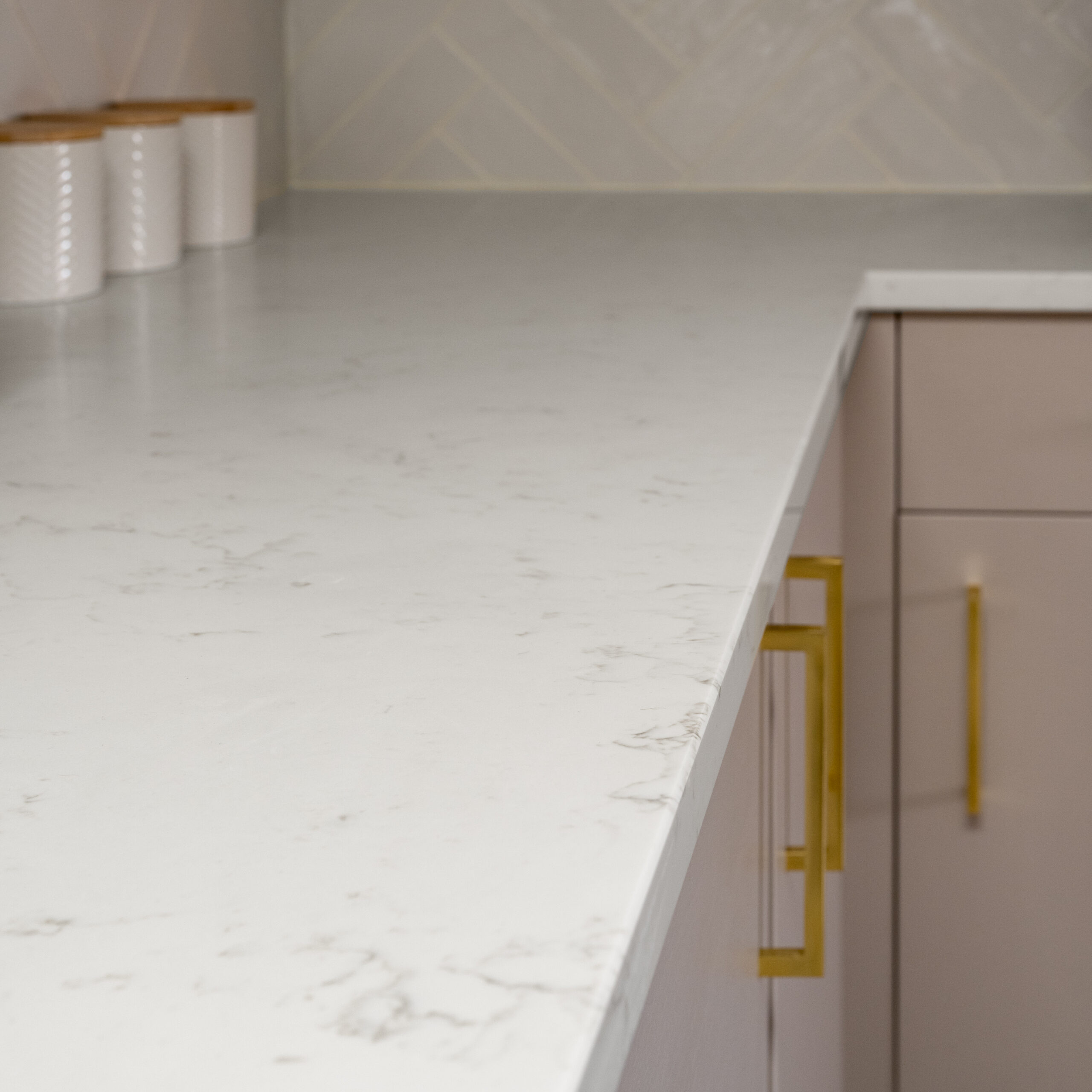 Carrara Quartz worktop with subtle grey veining in a modern kitchen featuring brass handles