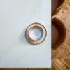 Top down view of Eternal Calacatta Quartz worktop with ceramic plates and warm toned chairs