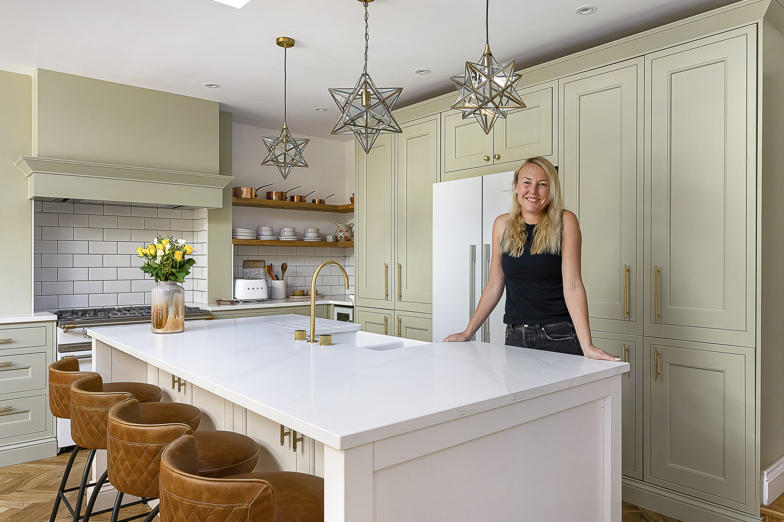 Customer standing in her kitchen with Eternal Calacatta Quartz worktops installed by Mayfair Worktops