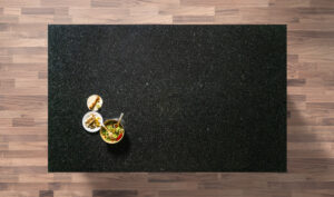 Overhead view of an Angola Black Granite worktop showing a dark speckled pattern, photographed from above with a small styled tray in the corner.