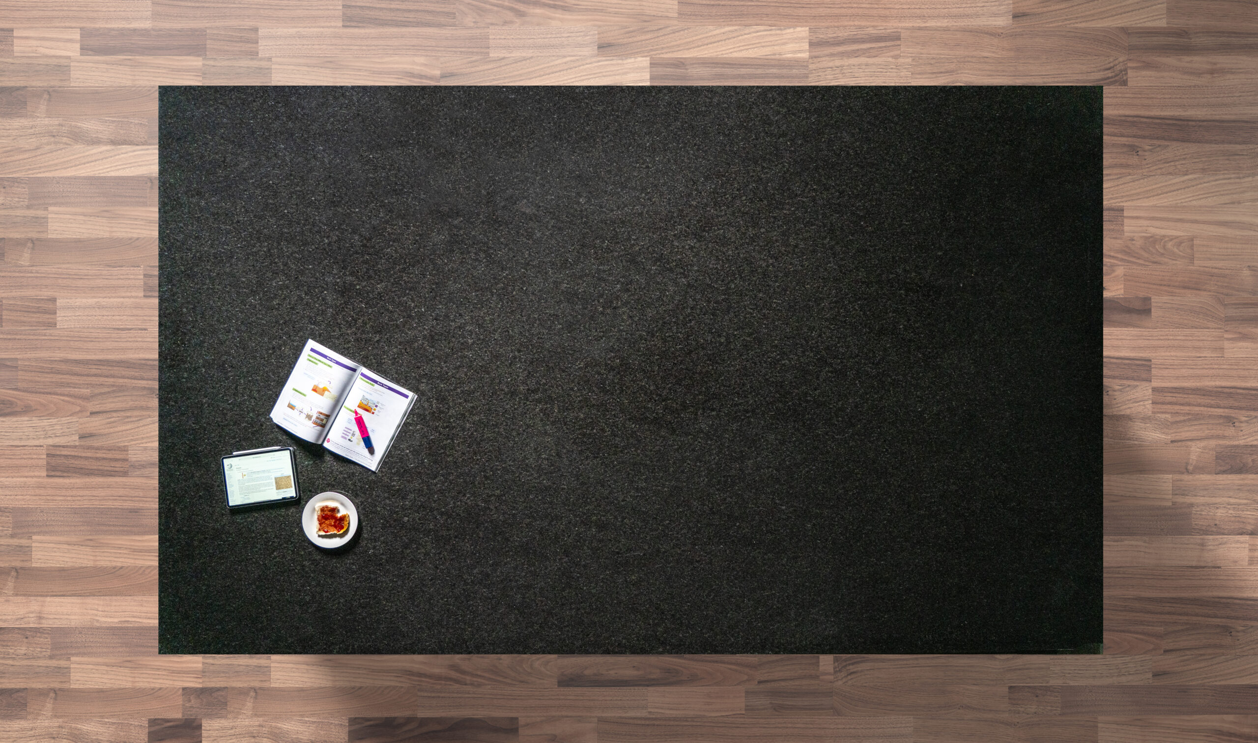 Overhead view of a Black Pearl Granite worktop showing the dark flecked pattern, photographed from above with a small styled tray in the corner.