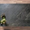 Overhead view of a Black Storm leathered Granite island worktop showing sweeping veining and a textured finish, styled with a small flower arrangement.