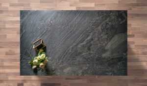 Overhead view of a Black Storm leathered Granite island worktop showing sweeping veining and a textured finish, styled with a small flower arrangement.