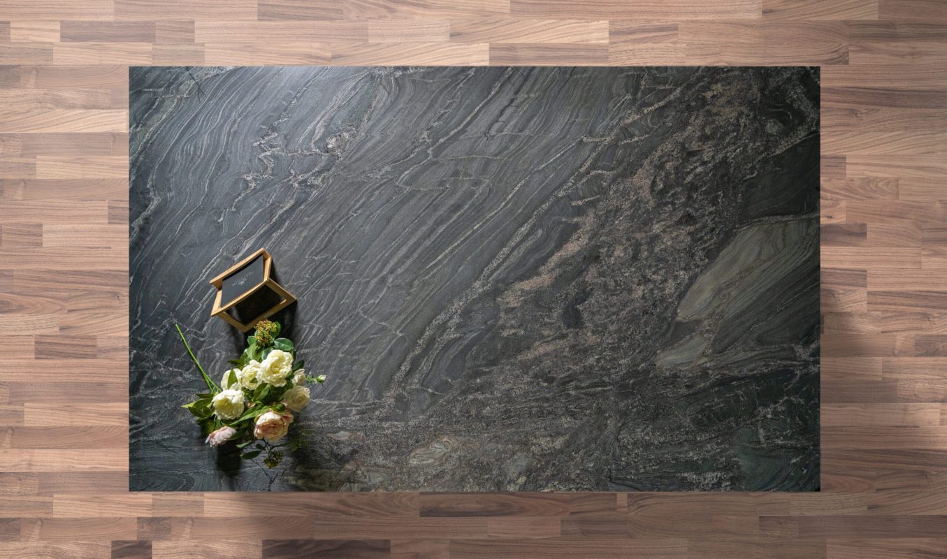 Overhead view of a Black Storm leathered Granite island worktop showing sweeping veining and a textured finish, styled with a small flower arrangement.