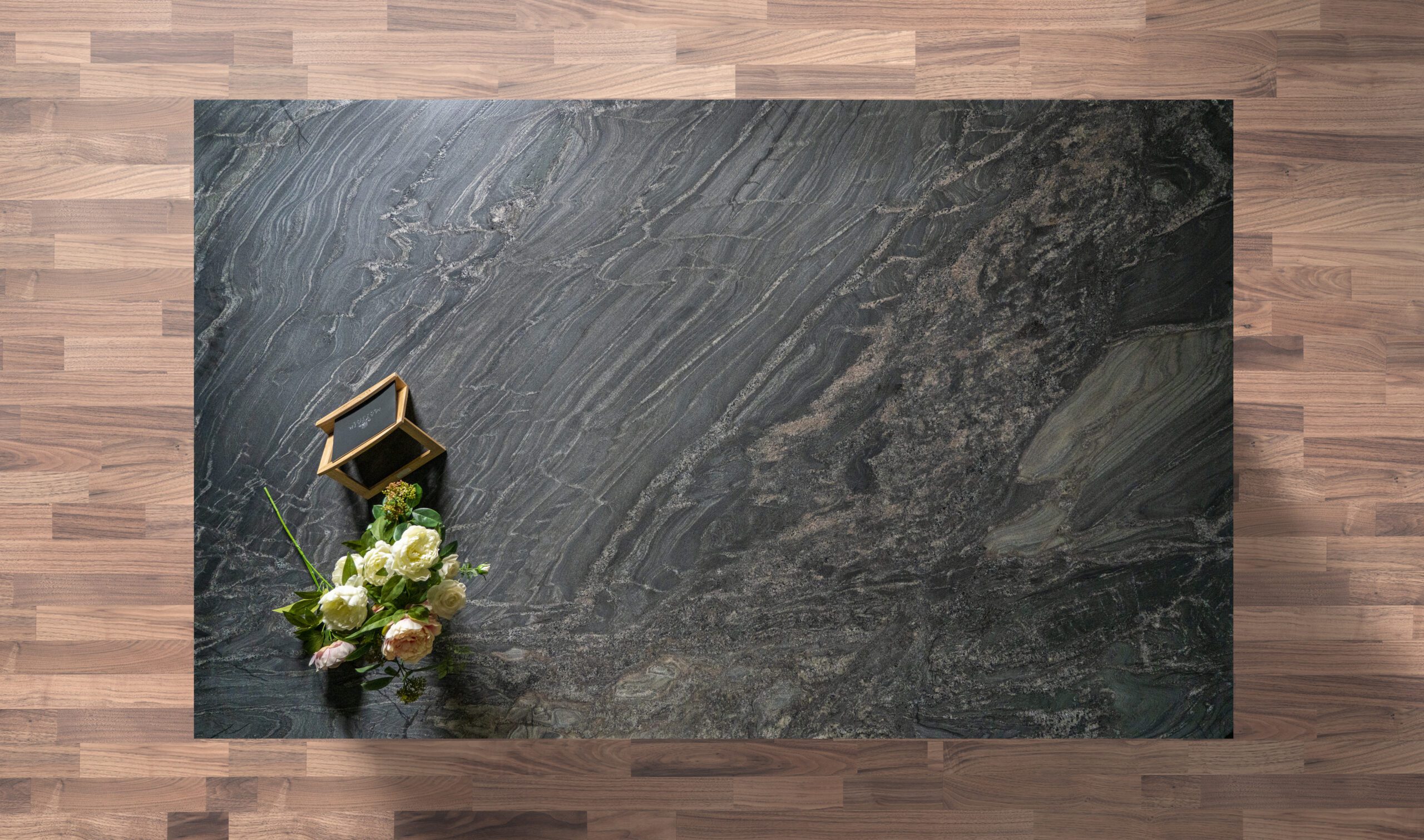 Overhead view of a Black Storm leathered Granite island worktop showing sweeping veining and a textured finish, styled with a small flower arrangement.
