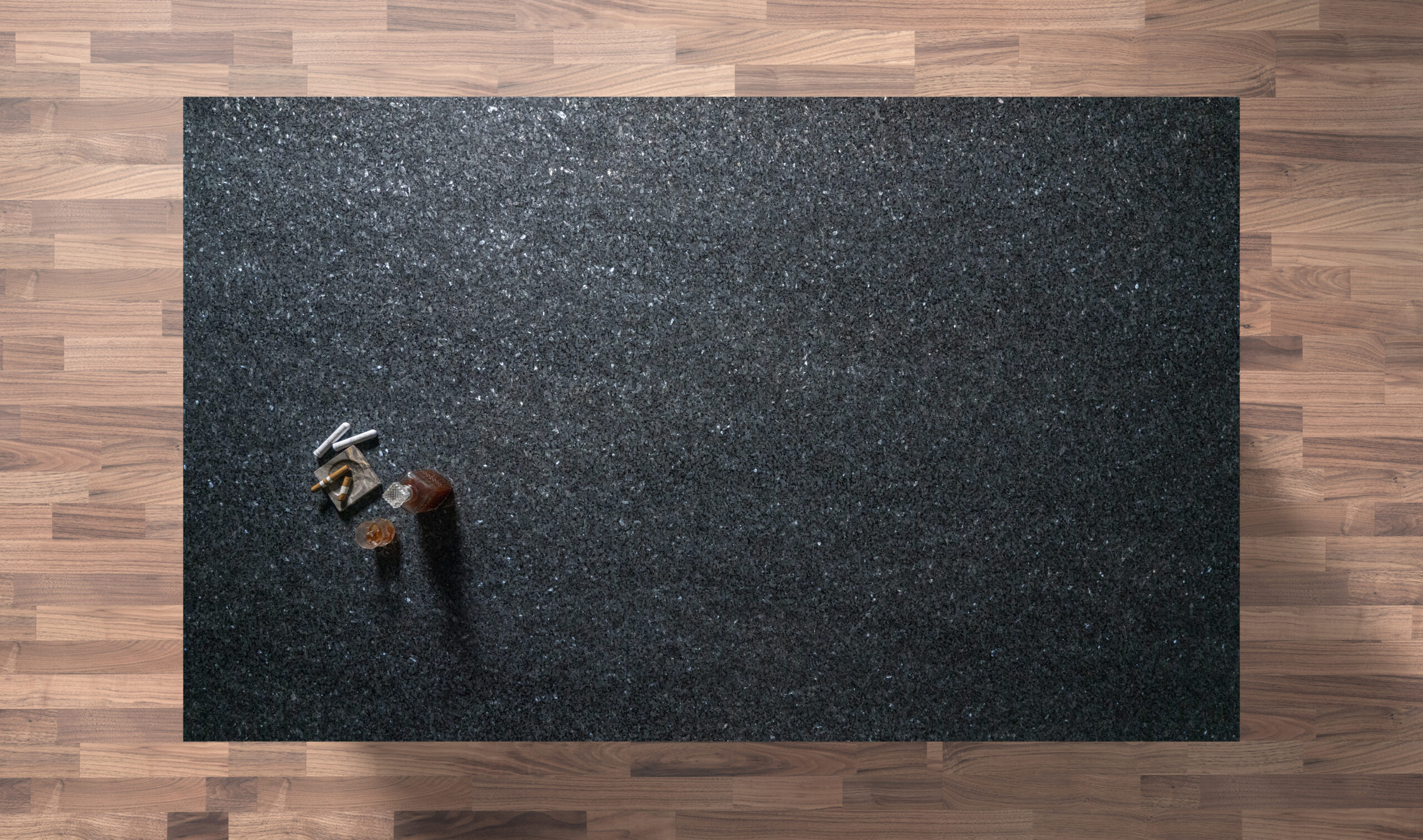 Overhead view of a Blue Pearl Granite worktop showing shimmering flecks across a dark surface, photographed from above with a small styled tray in the corner.