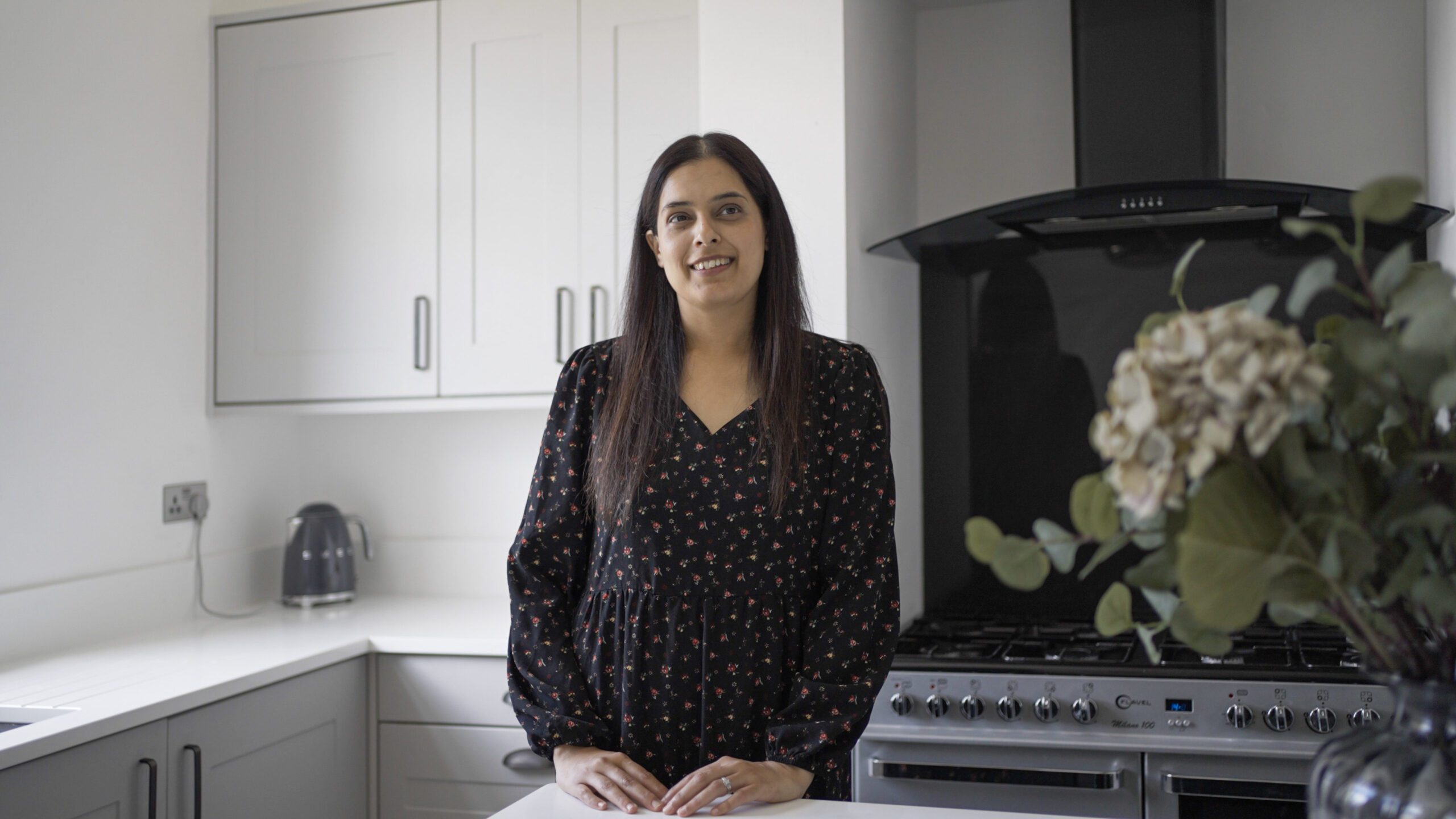Nadiya customer testimonial image in her kitchen with Classic White Quartz worktops visible in the background
