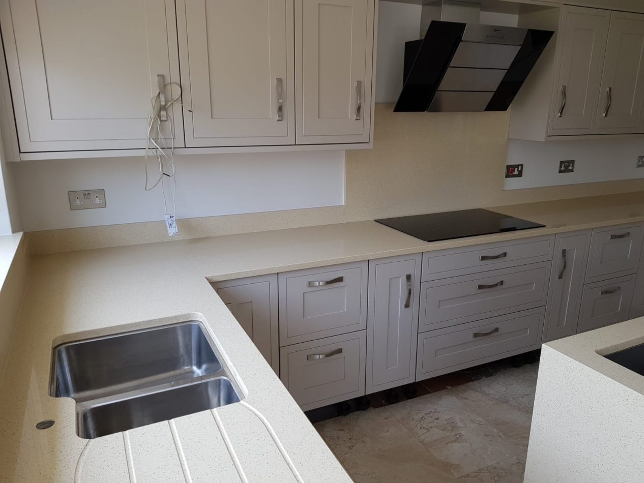 Beige Starlight Quartz worktop run with drainer grooves and hob cut-out showing warm beige surface in a light kitchen