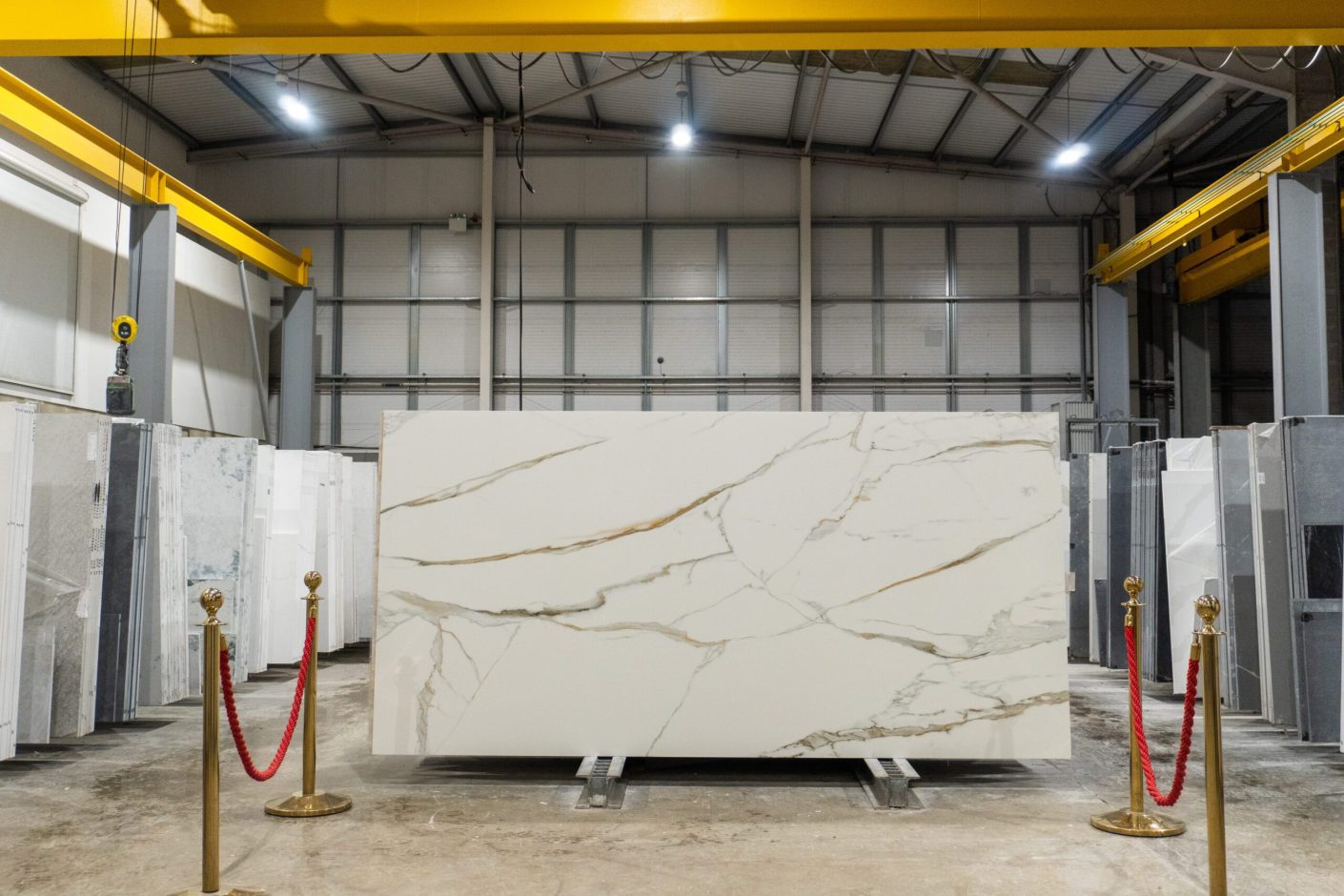 Full Calacatta Vagli Gold Porcelain slab standing in the workshop with bold gold veining on a white base