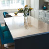 White Starlight Quartz kitchen island with subtle sparkle and vase of flowers in a modern kitchen