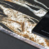 Noir St Laurent Porcelain worktop edge close-up with bold gold, copper and white veining on a deep black surface beside the hob.