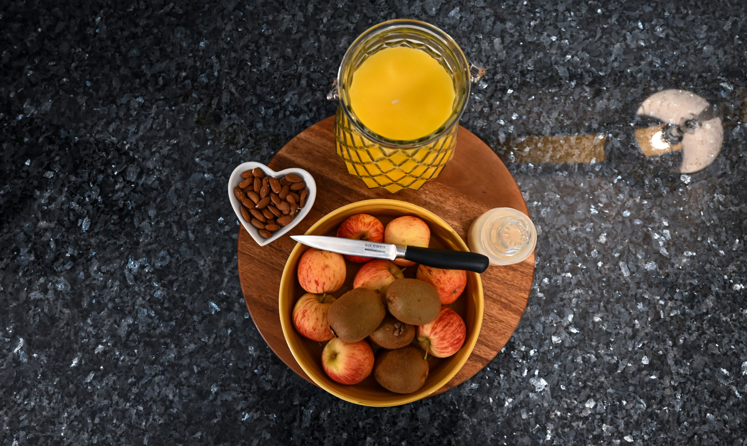 Overhead styling shot of a Blue Pearl Granite worktop with a breakfast tray, fruit bowl and orange juice, showing the dark speckled Granite surface.