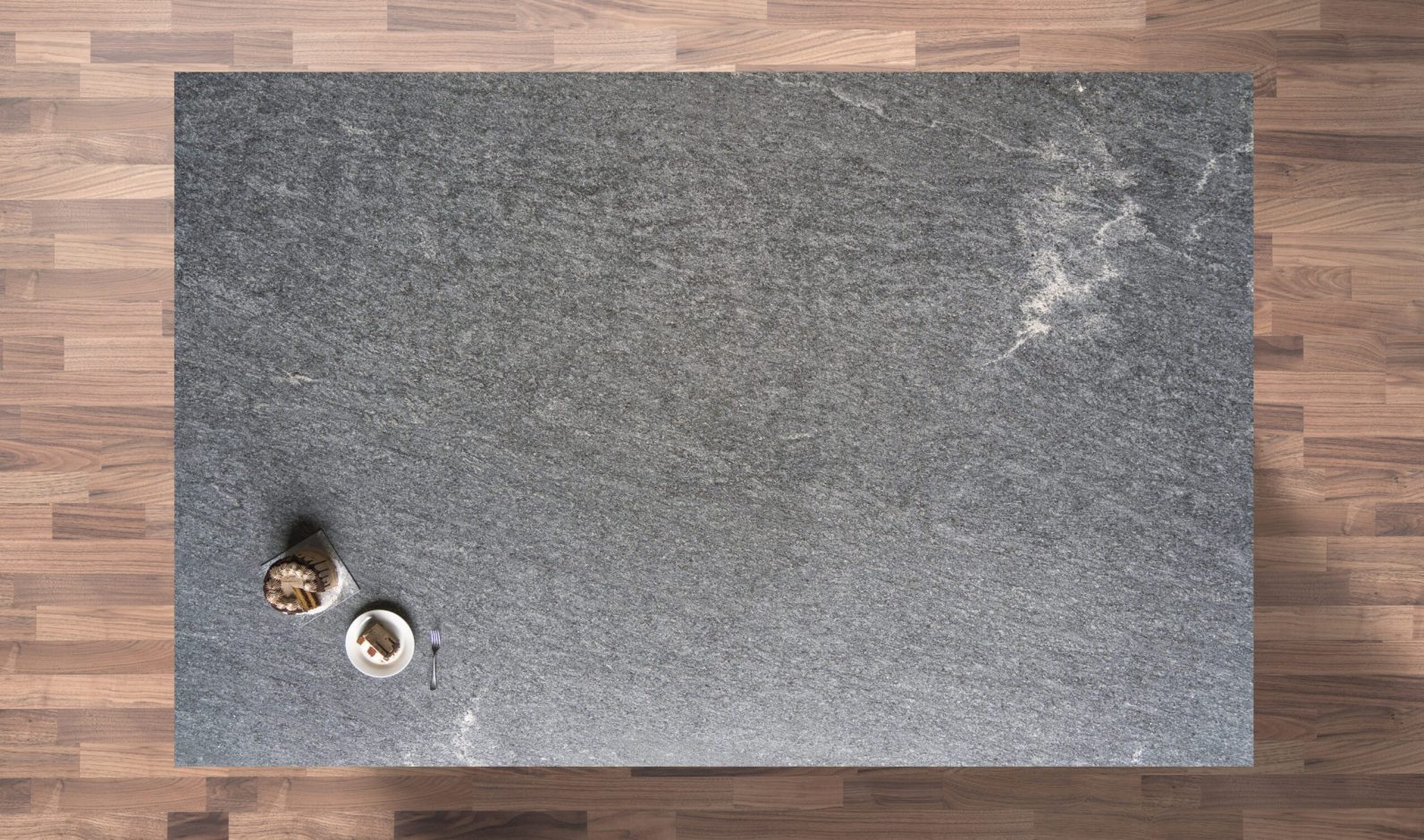 Overhead view of Diamond Galaxy leather Granite worktop showing a dark grey textured surface with subtle natural movement, photographed from above with styling near the edge.