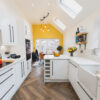 Long kitchen perspective showing Ice White Quartz worktops along white cabinets with a bright, smooth finish