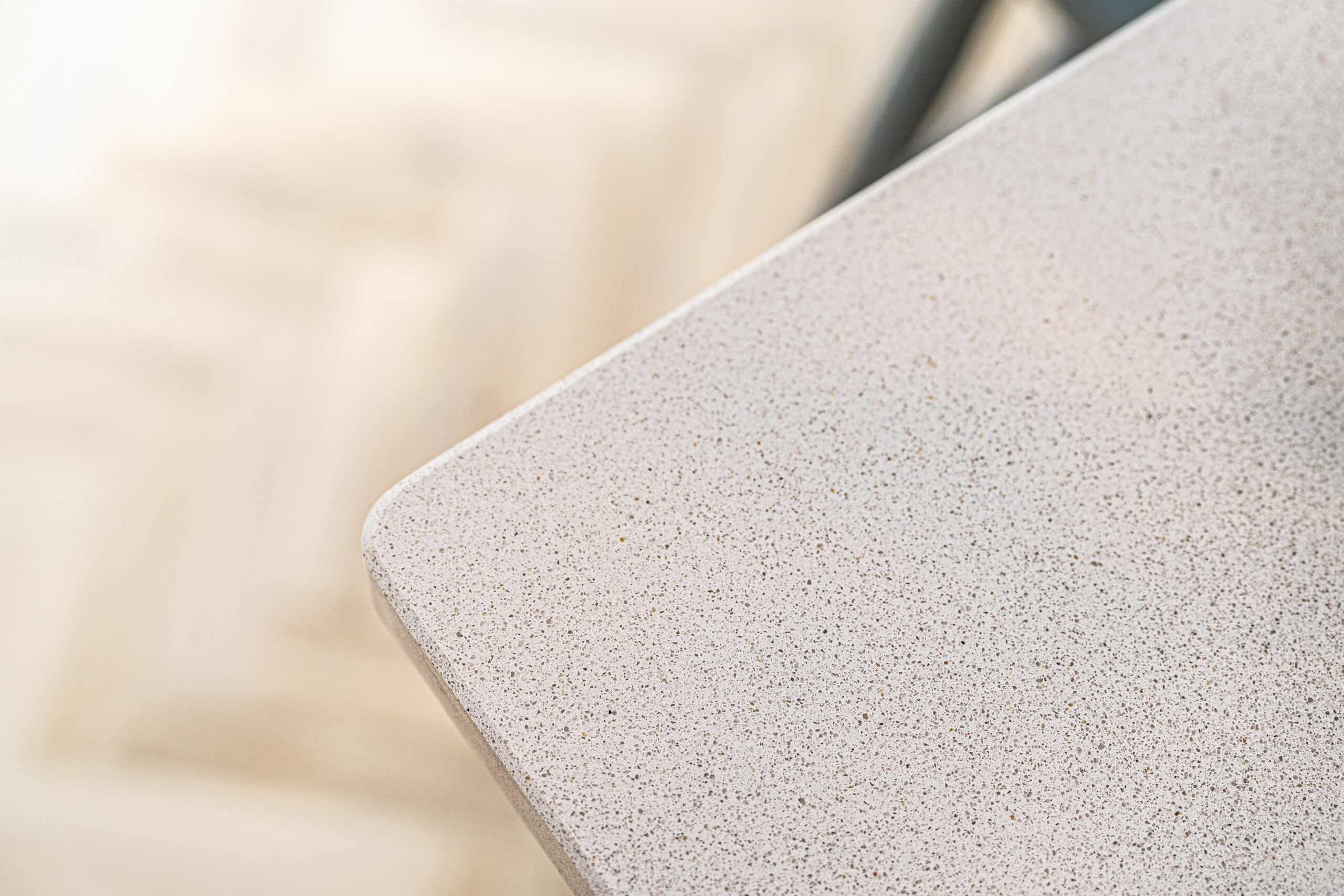 Close-up of Ice White Quartz worktop corner showing a rounded edge and fine speckled surface finish