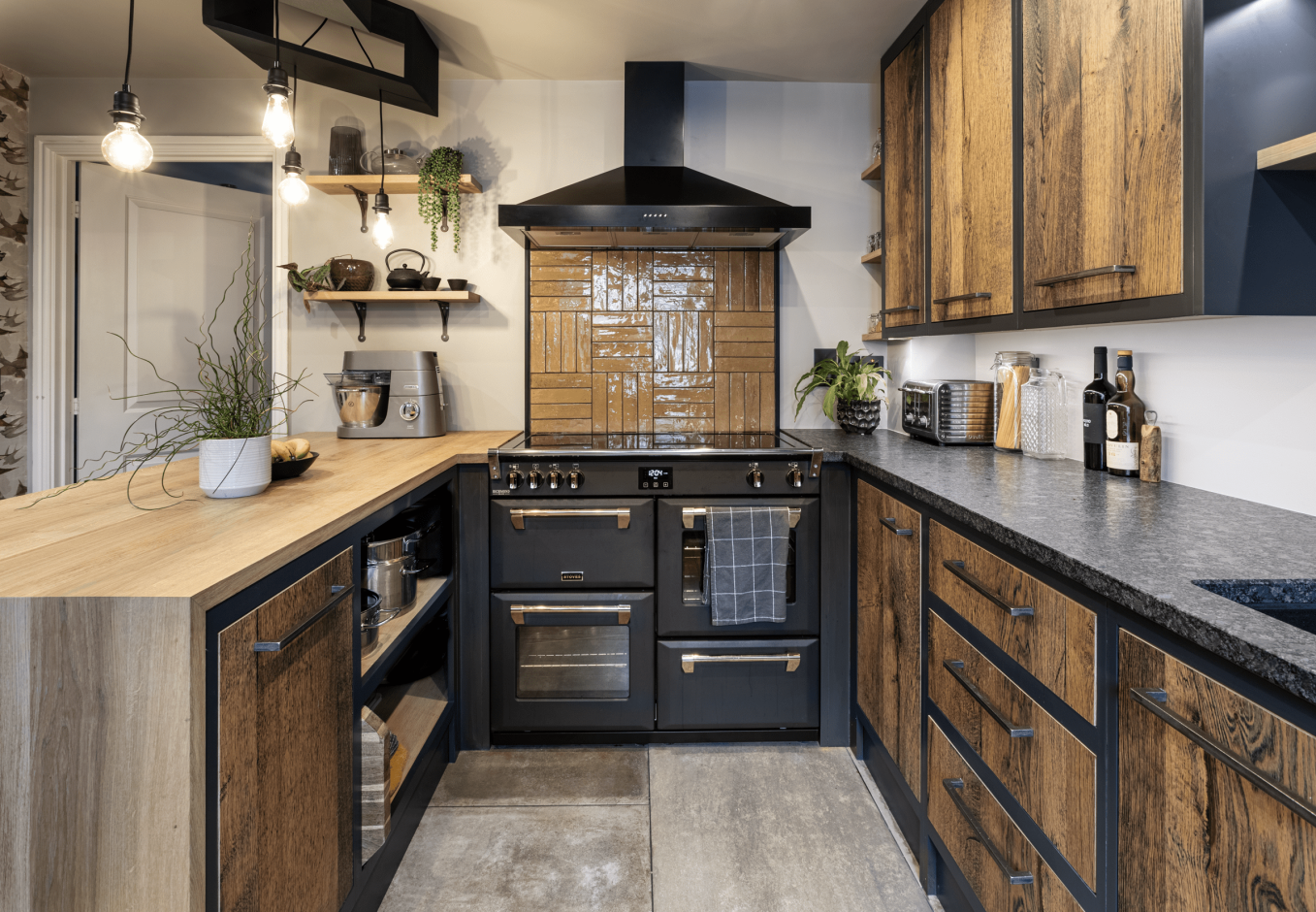 Wide kitchen view with Steel Grey leather Granite worktops on both sides, showing the textured Granite finish, rustic wood cabinetry and a black range cooker.