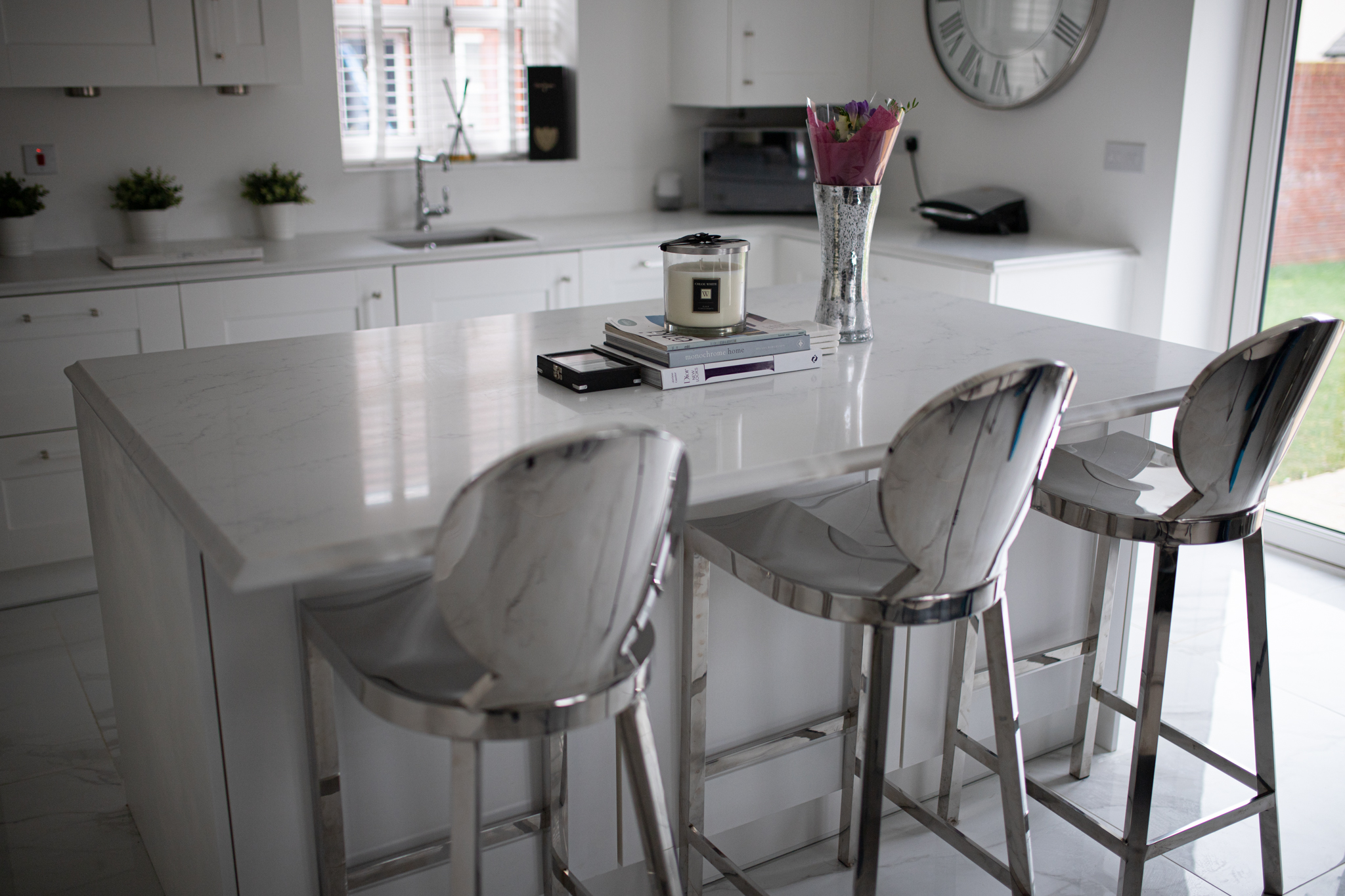 Modern kitchen featuring Statuario Bianco Porcelain island with bar stools and bright white cabinetry