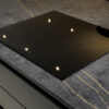 Laurent Porcelain worktop with gold veining and a flush black induction hob in a modern dark kitchen.
