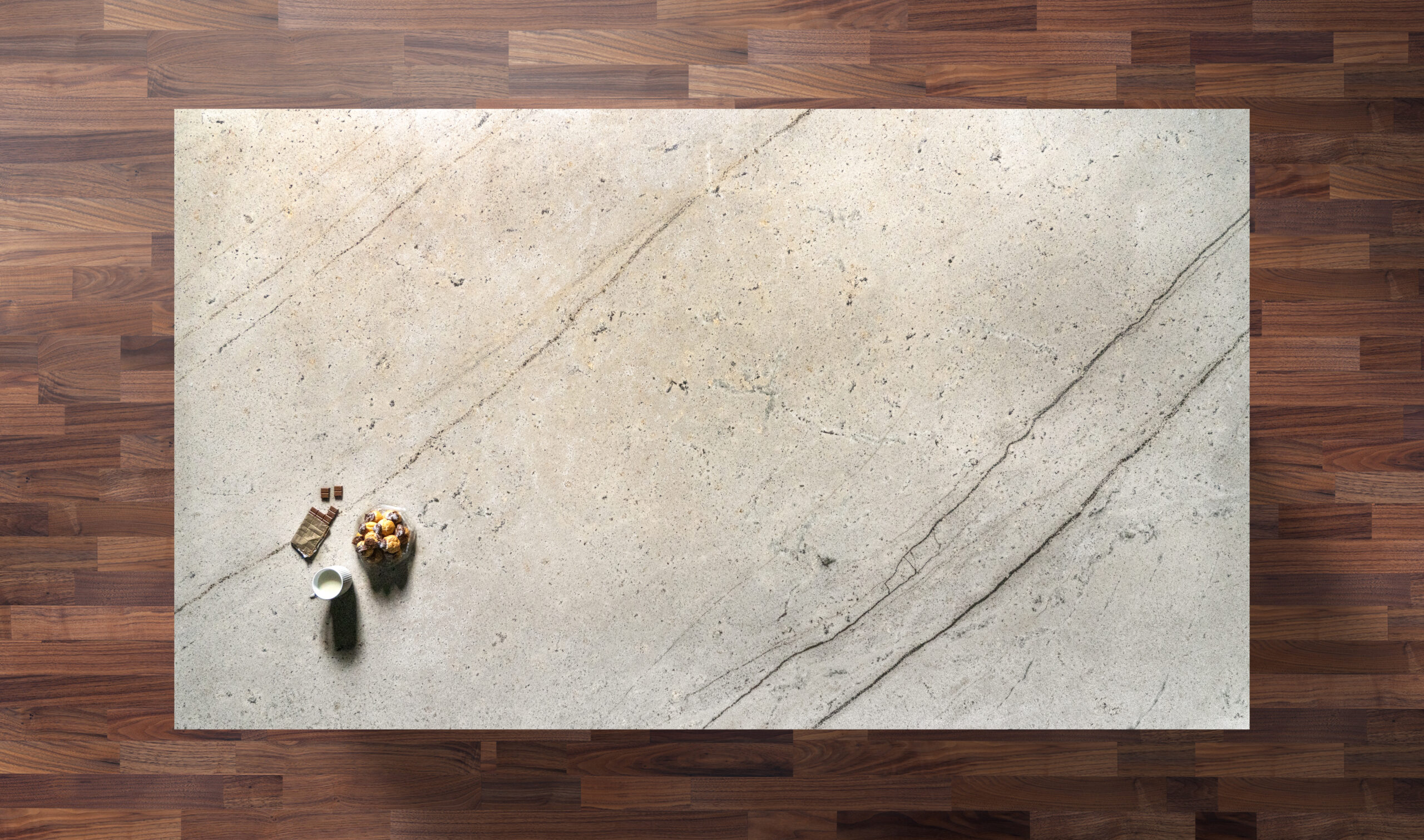 Overhead view of an Ivory Spice Granite worktop showing warm cream tones and soft natural veining, photographed from above with a small styled tray in the corner.