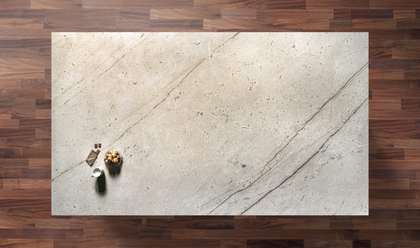 Overhead view of an Ivory Spice Granite worktop showing warm cream tones and soft natural veining, photographed from above with a small styled tray in the corner.