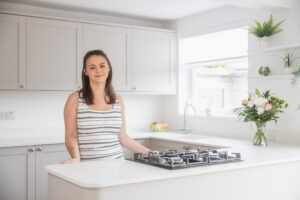 Megan customer testimonial image in her kitchen with Bluetta Carrara Quartz worktops visible around the hob