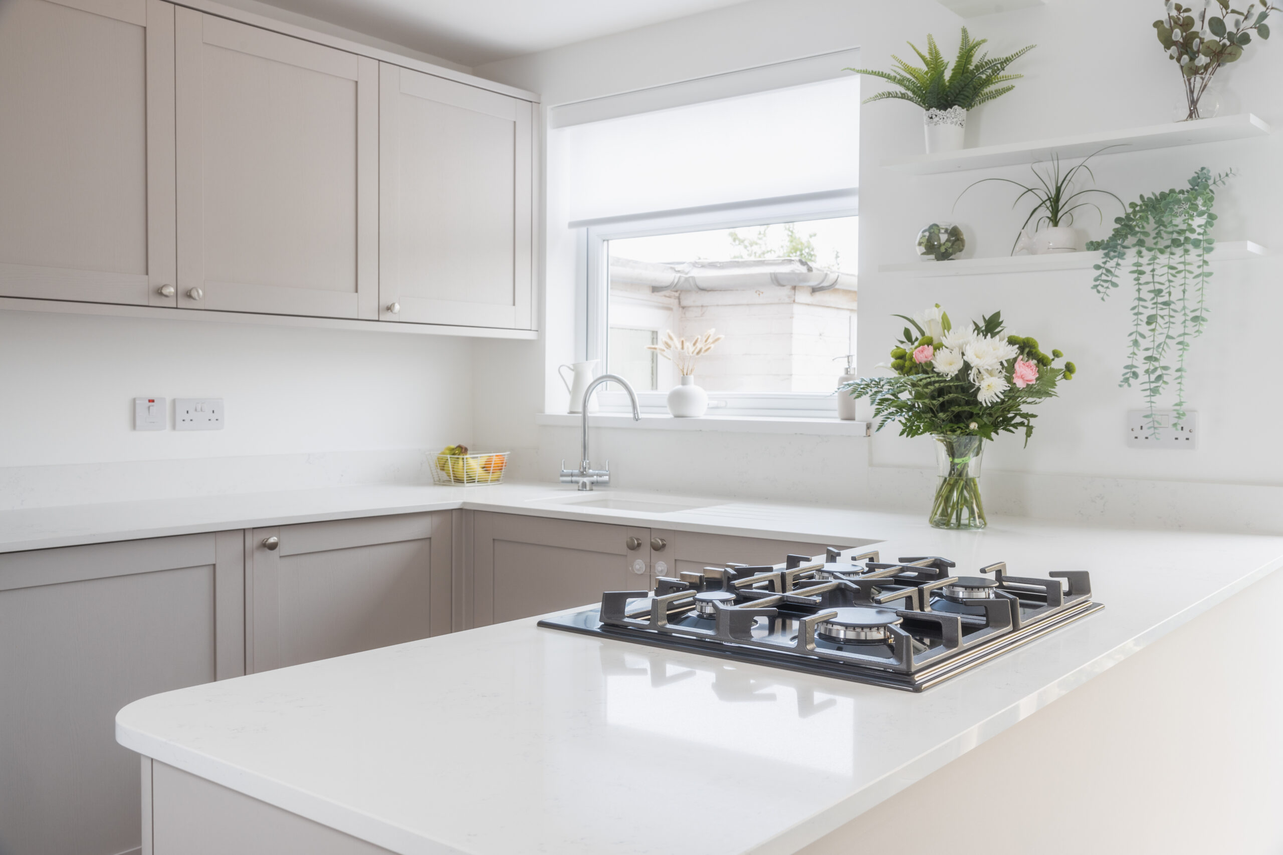 Bright kitchen view featuring Bluetta Carrara Quartz worktops with a hob set into the smooth white surface