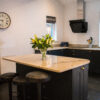 Wide kitchen view with an Ivory Spice Granite island worktop and breakfast bar seating, showing the warm cream Granite surface and dark cabinetry.