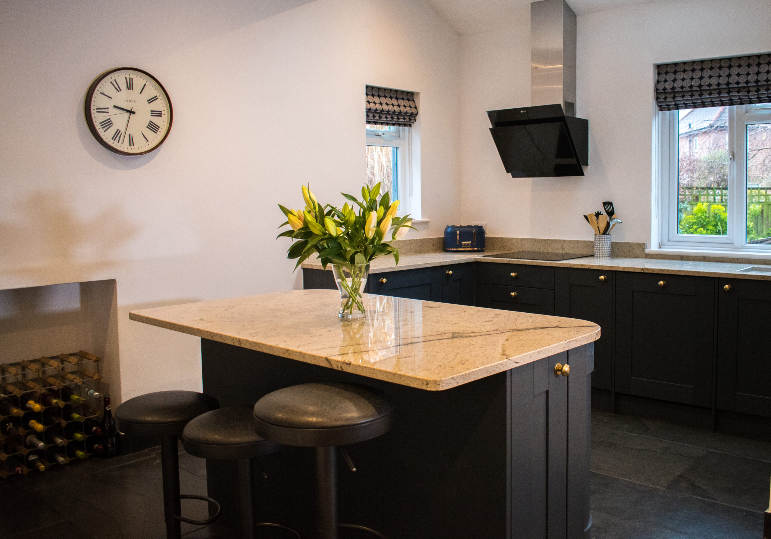 Wide kitchen view with an Ivory Spice Granite island worktop and breakfast bar seating, showing the warm cream Granite surface and dark cabinetry.
