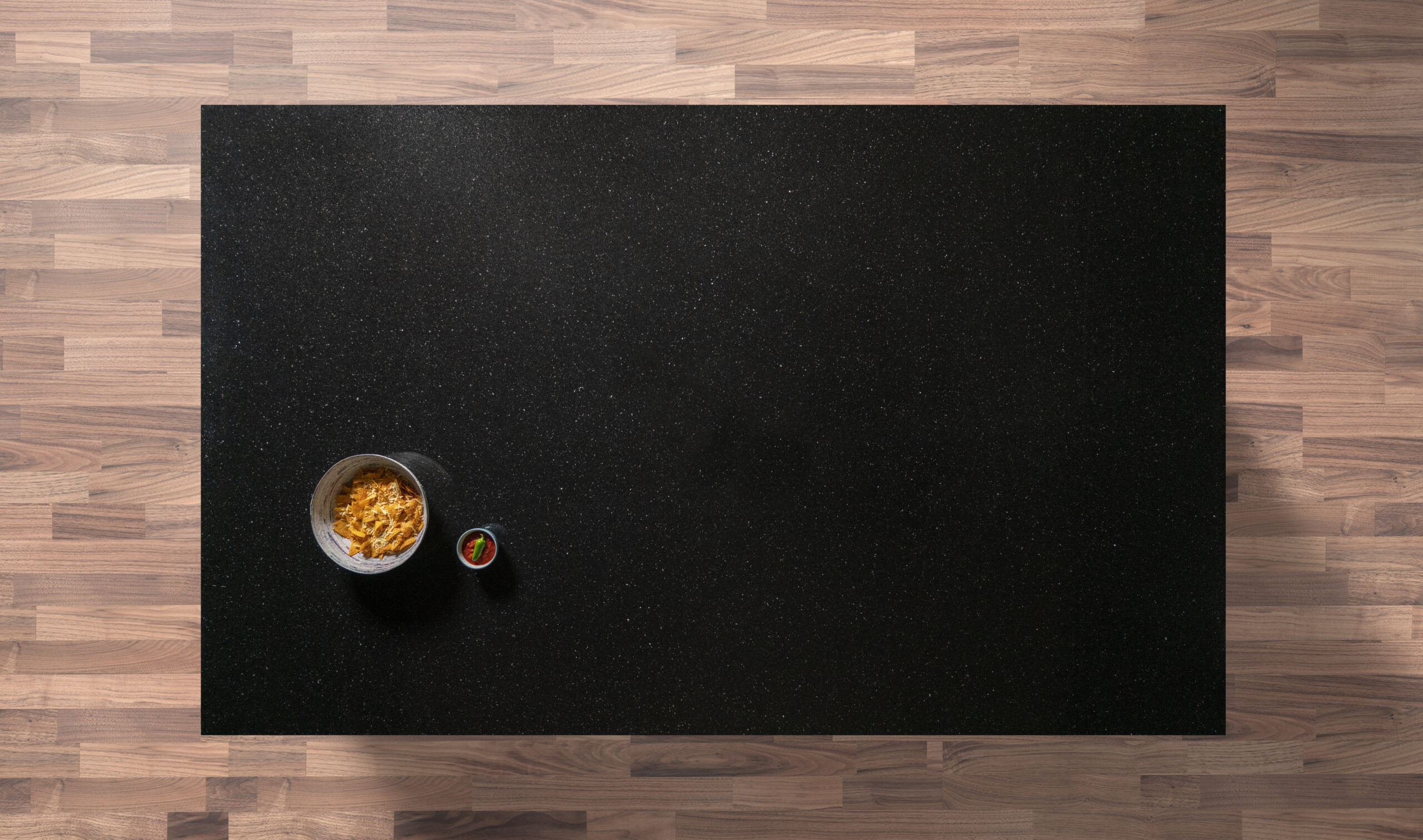 Overhead view of a Nero Cosmos Granite worktop showing a deep black surface with subtle sparkling flecks, photographed from above with a small styled tray in the corner.