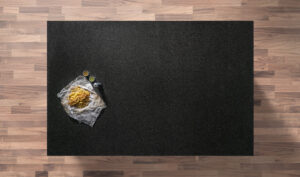 Overhead view of a Nero Impala Granite worktop showing a consistent dark grey speckled pattern, photographed from above with a small styled tray in the corner.