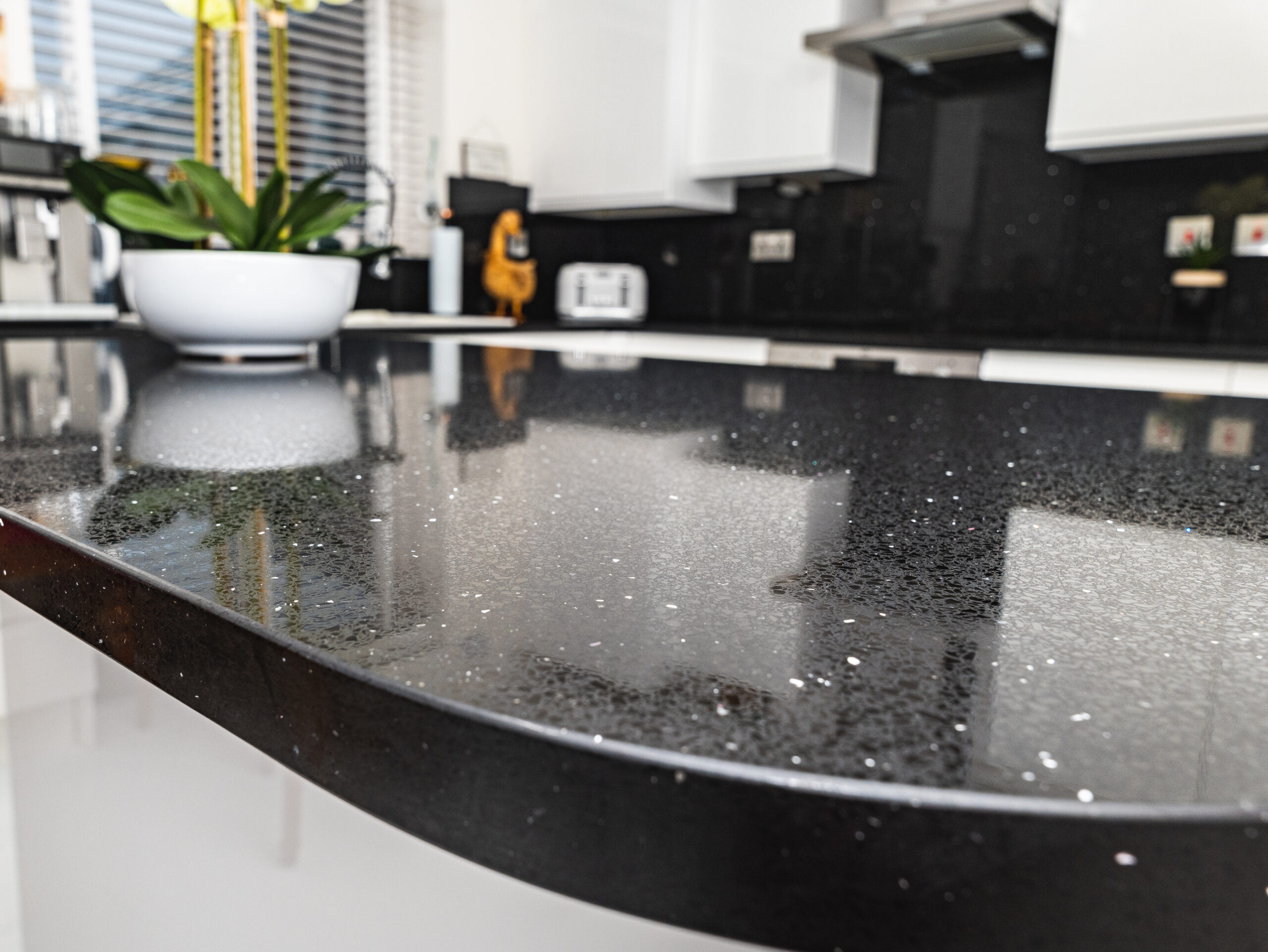Black Starlight Quartz worktop close-up showing reflective sparkle and a rounded island edge