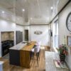 Wide angle view of a kitchen island with Ivory Fantasy Granite worktop and timber breakfast bar end, showing seating, range cooker and skylight ceiling.
