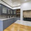 Wide kitchen view showing Ivory Fantasy Granite worktops along the main run and peninsula, with blue cabinetry, timber worktop section and a range cooker alcove.