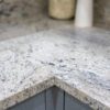 Close up of an Ivory Fantasy Granite worktop corner showing the polished edge detail and natural speckling across the surface.