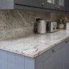 Corner view of Ivory Fantasy Granite worktop with matching Granite upstand, shown with kettle and toaster on a worktop run in a modern kitchen.