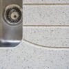 White Starlight Quartz worktop with drainer grooves beside a stainless steel sink