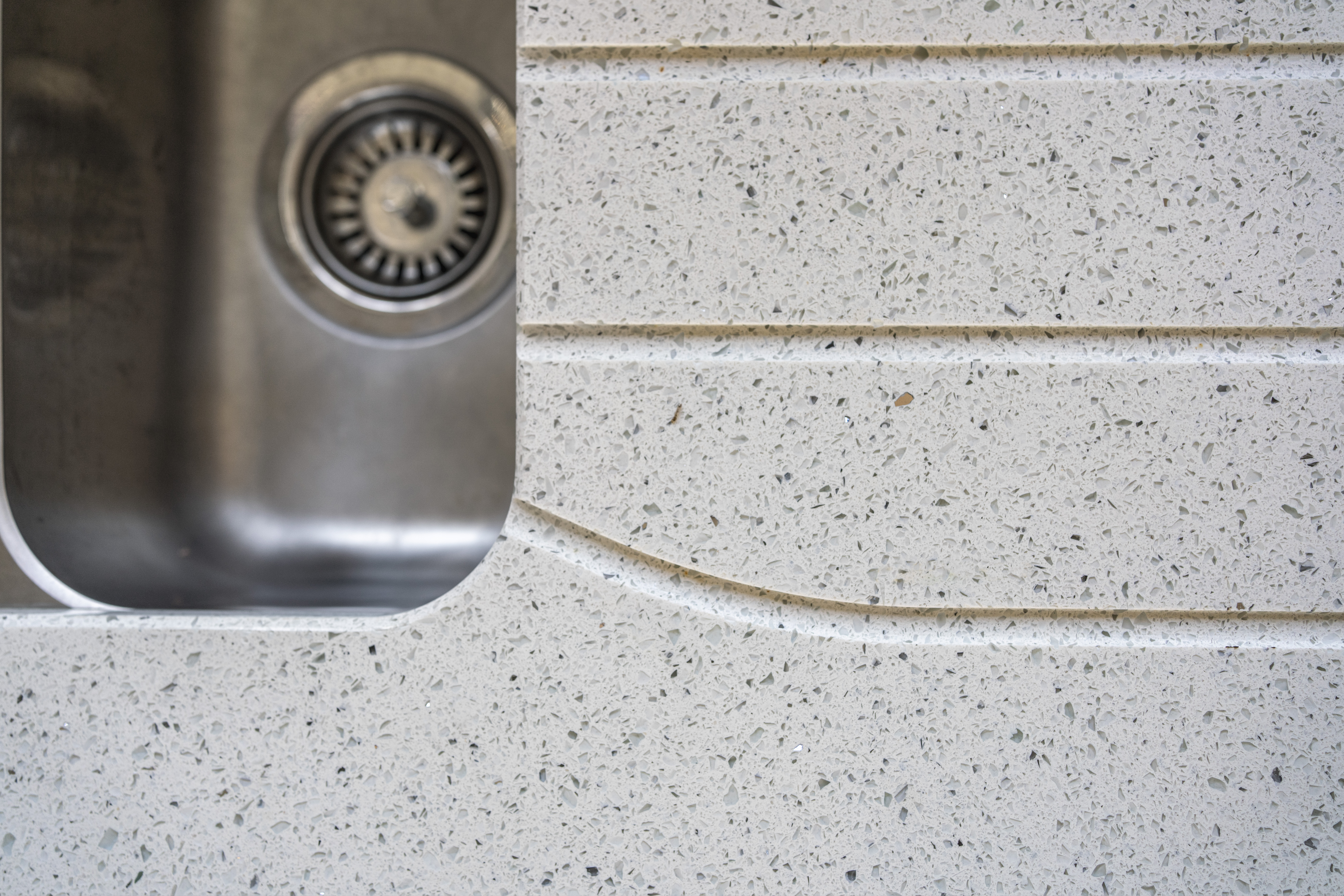 White Starlight Quartz worktop with drainer grooves beside a stainless steel sink
