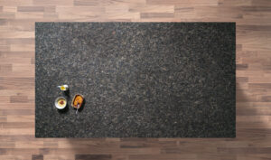 Overhead view of a Sapphire Brown Granite worktop showing a dense brown and black flecked pattern, photographed from above with a small styled tray in the corner.
