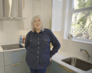 Anita in her kitchen with Dover White Quartz worktops visible around the sink and corner run